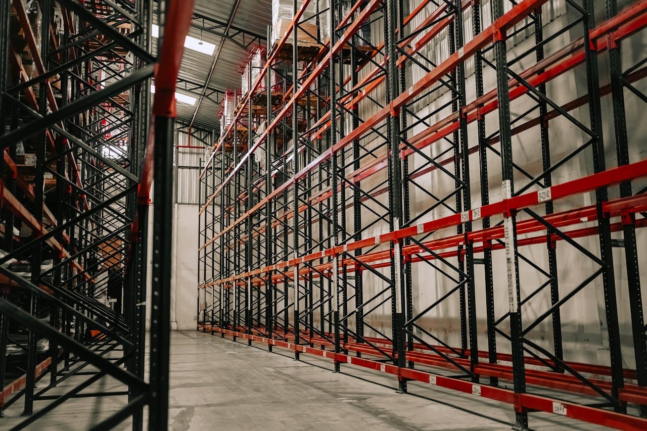 Spacious warehouse interior featuring empty metal racks and high ceiling.